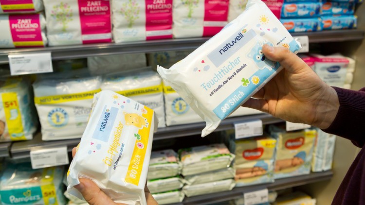 Zwei Hände halten Pflege- und Feuchttücher der Marke „natürlich“, im Hintergrund sind weitere Babypflegeprodukte im Regal.