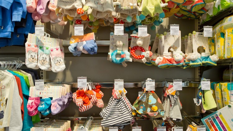 Regale mit Babysocken, Babyschuhen, Greiflingen und anderen Babyartikeln sowie Pampers-Windeln auf der rechten Seite.