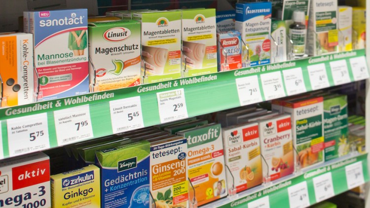 Regale mit Gesundheitsprodukten wie Magentabletten, Kohletabletten und Nahrungsergänzungsmitteln, Preisschilder darunter.