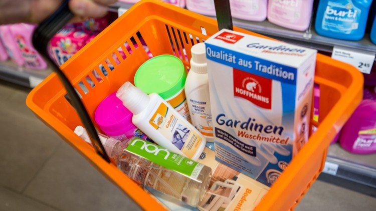 Orange Einkaufskorb mit Putz- und Waschmitteln wie Gardinenwaschmittel von Hoffmanns und weiteren Hygieneartikeln.