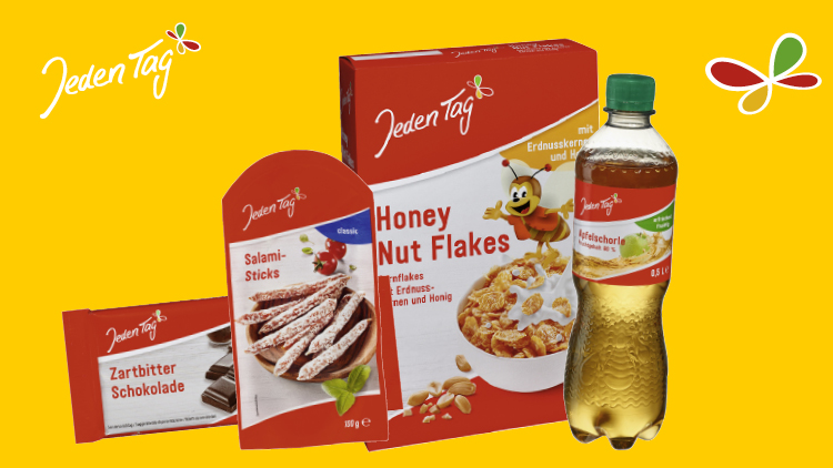 Produkte der Marke „Jeden Tag“ vor gelbem Hintergrund, darunter Zartbitterschokolade, Salami-Sticks, Honey Nut Flakes und Apfelschorle.