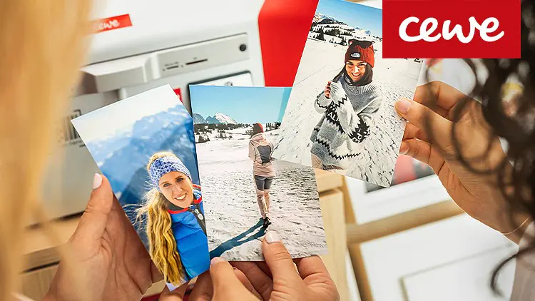 Drei Hände halten Winterfotos vor einem weißen Fotodruckterminal, oben rechts rotes Logo mit weißem CEWE-Schriftzug.