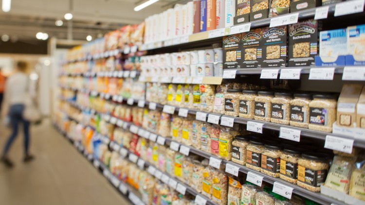 Regale in einem GLOBUS Markt mit Müsli, Nüssen und Haferflocken in verschiedenen Verpackungen, davor unscharfe Person.