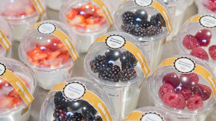 Mehrere Becher mit Joghurt und frischen Früchten wie Brombeeren, Himbeeren und Erdbeeren, mit gelbem GLOBUS-Frische-Etikett.