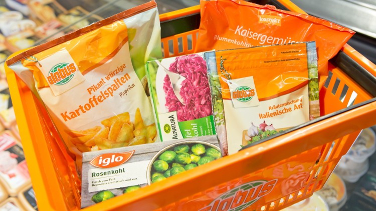 Ein orangefarbener GLOBUS-Einkaufskorb mit Tiefkühlprodukten, darunter Kartoffelspalten, Rosenkohl und Kaisergemüse.