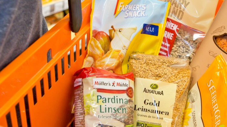 Oranger Einkaufskorb mit Pardina Linsen, Gold Leinsamen, Apfelchips und Sonnenblumenkernen in verschiedenen Verpackungen.
