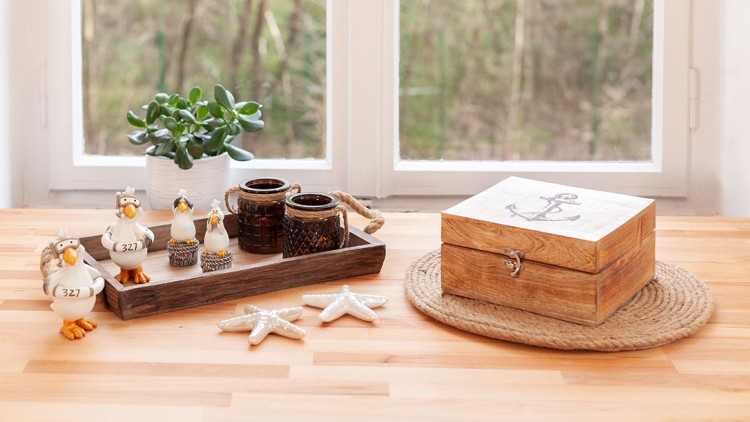 Holztablett mit Keramikmöwen, zwei braunen Kerzenhaltern, Sukkulente, Holzbox mit Anker und zwei Deko-Seesternen.