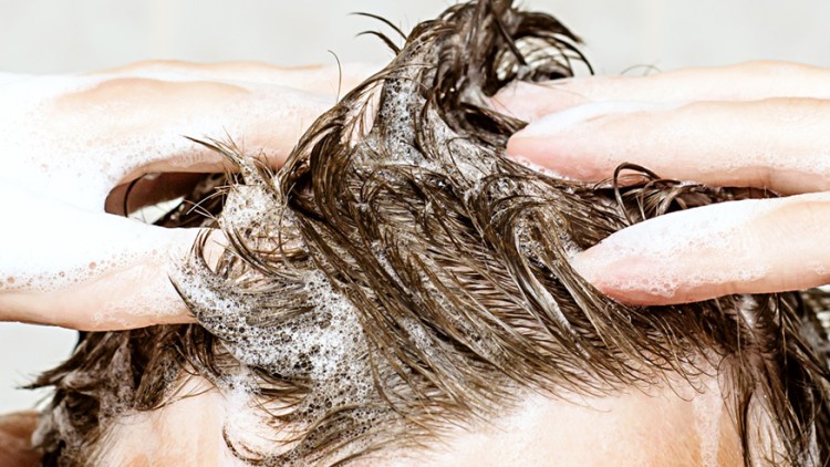 Zwei Hände schäumen mit Shampoo Haare ein, Schaum und nasses Haar sind deutlich sichtbar.