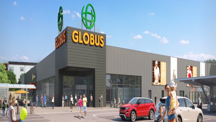 Eingangsbereich eines GLOBUS Marktes mit großer Glasfront, orangenem Logo, parkenden Autos und Personen auf dem Parkplatz.