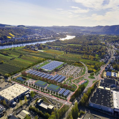 Luftaufnahme eines GLOBUS Marktes mit Solaranlagen auf dem Dach, großem Parkplatz, Grünflächen und umliegender Landschaft.
