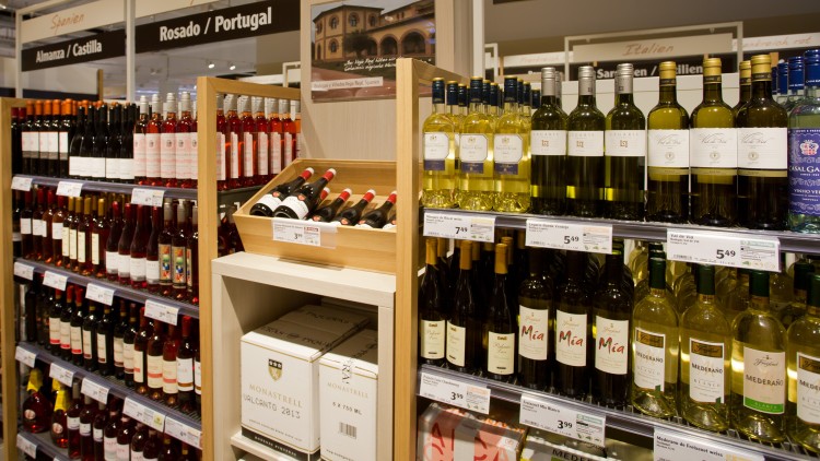 Weinregal mit spanischen Rot-, Weiß- und Roséweinen, darüber Schilder mit den Kategorien wie Almansa und Bianco.