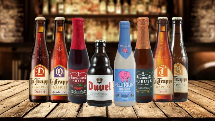 Acht verschiedene Bierflaschen mit Etiketten von Marken wie La Trappe, Lindemans, Duvel und Delirium auf einem Holztisch.