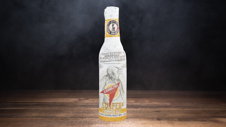 Eine in Papier eingewickelte Flasche auf Holzuntergrund mit der Aufschrift „Saufers Summer Ale, alkoholfrei“.