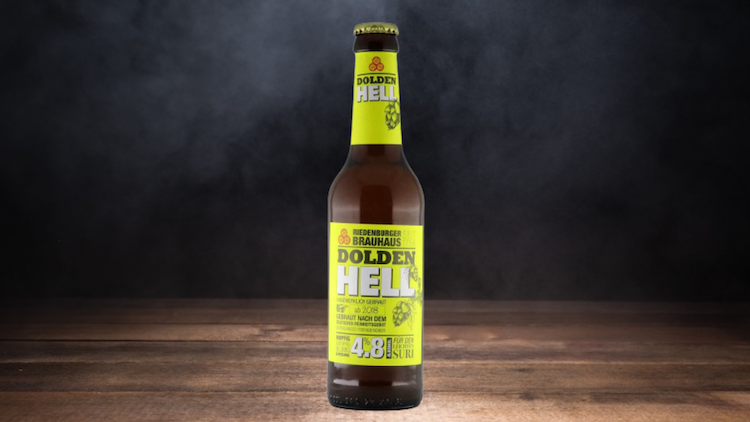 Braune Bierflasche mit gelbem Etikett, Aufschrift „Dolden Hell“ und Angabe „4,8 % vol“, auf Holzuntergrund vor dunklem Hintergrund.