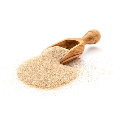 Ein Holzlöffel liegt auf einer hellen Fläche und ist mit beigem, feinkörnigem Pulver gefüllt, das teils herausgerieselt ist.