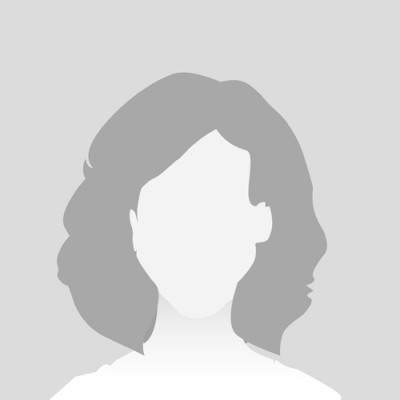 Ein schattiertes Porträt einer Person mit schulterlangem Haar vor einem neutral grauen Hintergrund.