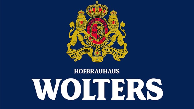 Wappen mit zwei goldenen Löwen, Krone und rotem Schild, darunter der Text „HOFBRAUHAUS WOLTERS“ in weißen Buchstaben auf blauem Hintergrund.