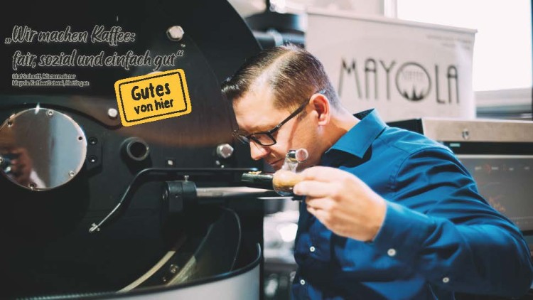 Ein Mann in blauem Hemd arbeitet an einer Kaffeeröstmaschine, Text: „Wir machen Kaffee: fair, sozial und einfach gut“.