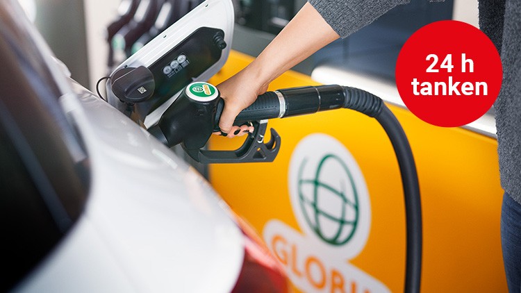 Eine Hand hält eine Zapfpistole an einem weißen Auto, Hintergrund mit GLOBUS-Logo und rotem Kreis mit Text \