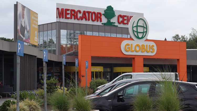 Der Eingangsbereich eines GLOBUS Marktes mit orangefarbener Fassade, Parkplätzen und dem Schriftzug „MERCATOR CENTER“.