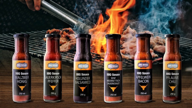 Sechs BBQ-Saucen von BBQ Zirkus mit Textsorten wie Malzbier Honig und Apfelwein Bacon vor Grill mit Fleisch, Flammen und Rauch.