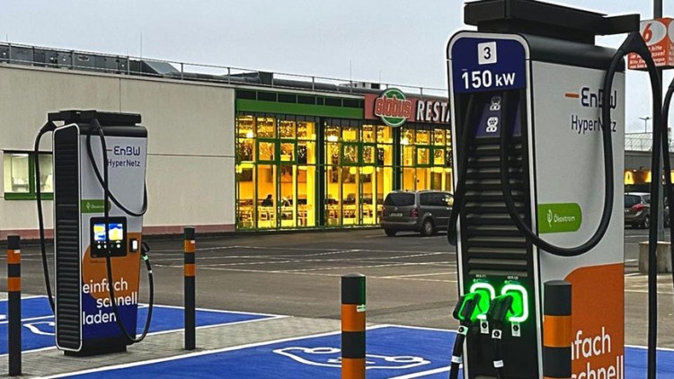 Ladesäulen des EnBW HyperNetz auf blau markierten Parkflächen, im Hintergrund das GLOBUS Restaurant mit beleuchteten Fenstern.