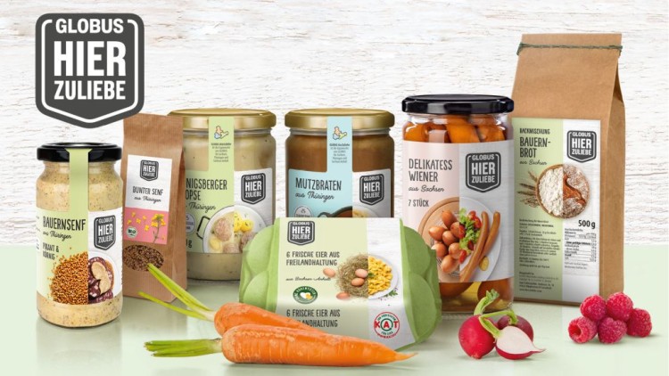 Produkte der Marke GLOBUS HIER ZULIEBE wie Senf, Brotbackmischung und Gemüse, auf einem hellen Untergrund arrangiert.