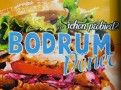 Nahaufnahme eines Döners mit Salat und Gemüse, Text im Bild: „...schon probiert? BODRUM Döner“.