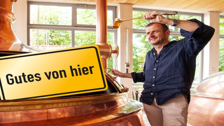 Person steht vor einer kupfernen Brauanlage, hält eine Schöpfkelle hoch, daneben ein Schild mit der Aufschrift Gutes von hier.