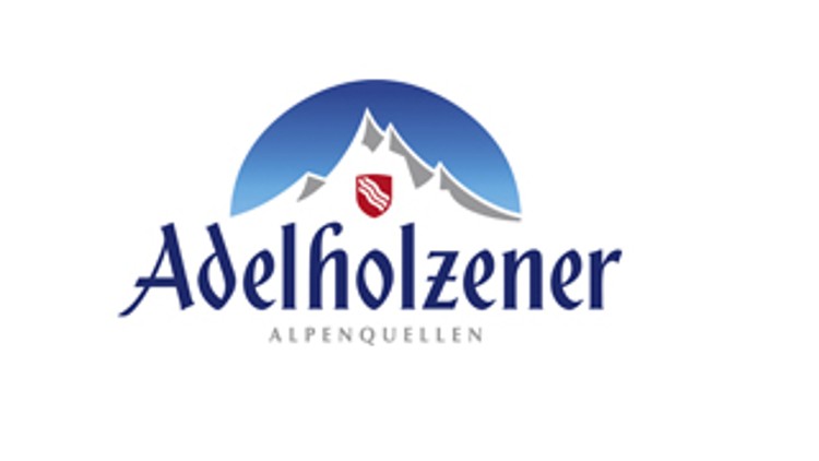 Blau-weißer Schriftzug „Adelholzener Alpenquellen“ mit Bergsilhouette und rotem Wappen vor einem blauen Halbkreis.