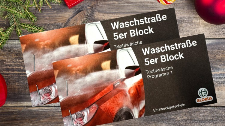 Zwei Gutscheinkarten mit Text „Waschstraße 5er Block, Textilwäsche Programm 1, Einzweckgutschein“ liegen auf einem Holztisch.