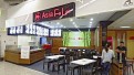 Asiatisches Restaurant mit Holztheke, schwarzen Tischen und Stühlen, beleuchteten Speiskarten und Schriftzug „Asia Fu Loi“.