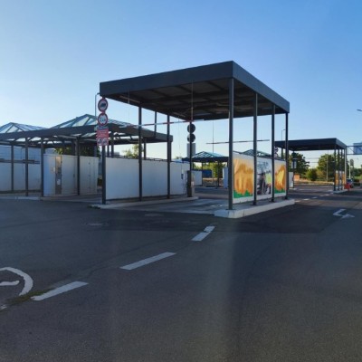 Ein leerer Parkplatz mit Überdachung, GLOBUS Logo im Hintergrund, klare Fahrbahnmarkierungen und aufgehängte Verkehrsschilder.