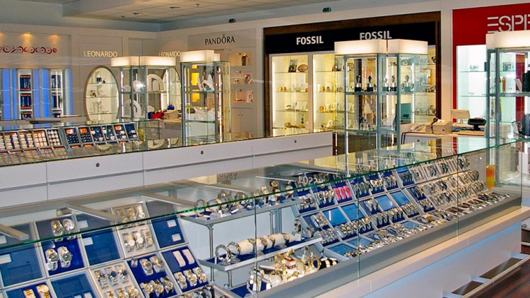 Ein Geschäft mit beleuchteten Glasvitrinen voller Schmuck und Uhren, Marken wie LEONARDO, PANDORA, FOSSIL und ESPRIT sind sichtbar.