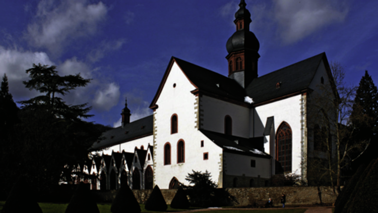 Eine historische Kirche mit weißer Fassade, dunklem Dach und Turm unter blauem Himmel mit vereinzelten Wolken.