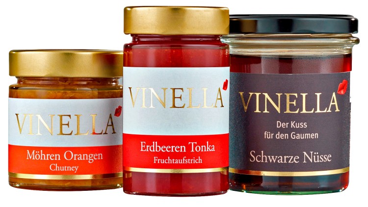 Drei Gläser mit goldenem oder schwarzem Deckel, Aufschriften: Möhren Orangen Chutney, Erdbeeren Tonka Fruchtaufstrich, Schwarze Nüsse.