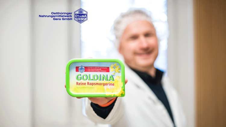 Eine grüne Packung Goldina Reine Rapsmargarine wird in der Hand gehalten, daneben steht das Logo der Othüna GmbH.