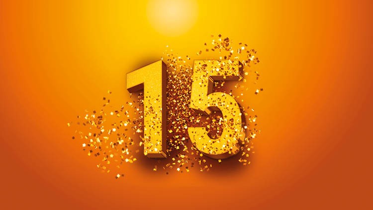 Goldene Zahl 15, umgeben von glitzernden Partikeln, auf einem leuchtenden orangefarbenen Hintergrund mit heller Lichtquelle oben.