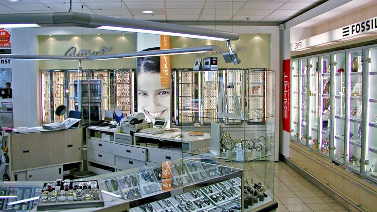 Verkaufsbereich mit Glasvitrinen voller Schmuck und Uhren, Marken wie Esprit und Fossil sind über den Vitrinen beschriftet.