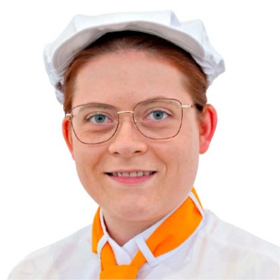 Person in weißer Kopfbedeckung und weißem Oberteil mit orangefarbenem Halstuch auf weißem Hintergrund.