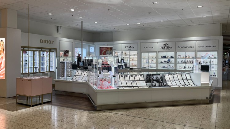 Schmuck- und Uhrenverkaufsfläche mit Glasvitrinen, beleuchteter Theke sowie Markenlogos wie Fossil, Skagen und Festina.