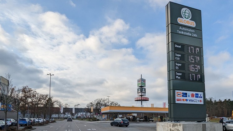 Mehrspurige Zufahrtsstraße zur GLOBUS Automatentankstelle mit Preistafel und Zapfsäulen neben einem Globus Baumarkt.