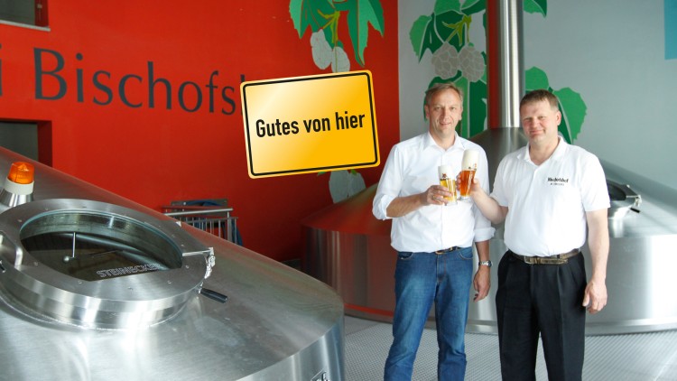 Zwei Personen stoßen mit Biergläsern an, im Hintergrund großer Schriftzug „Bischofs“ und Schild „Gutes von hier“.