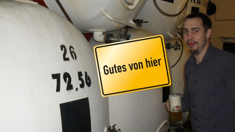 Weiße Tanks mit schwarzen Zahlen und einem gelben Schild mit der Aufschrift Gutes von hier, daneben ein Glas Bier.