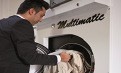 Person legt helle Wäsche in eine geöffnete Waschmaschine mit dem Schriftzug „Multimatic“.