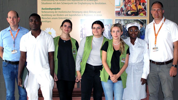 Eine Gruppe von Mitarbeitenden steht vor einer Wand mit Text und Bildern zu Auslandprojekten der Globus-Stiftung.
