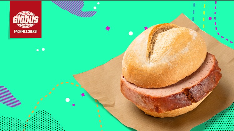 Eine knusprige Semmel mit einer dicken Scheibe Leberkäse liegt auf braunem Papier, oben links das Logo der GLOBUS Fachmetzgerei.