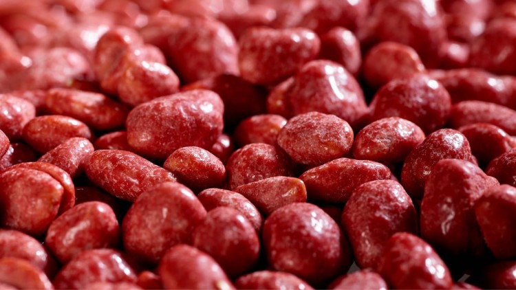 Nahaufnahme von glänzenden, rot überzogenen Erdnüssen in Zuckerkruste, dicht beieinander liegend.