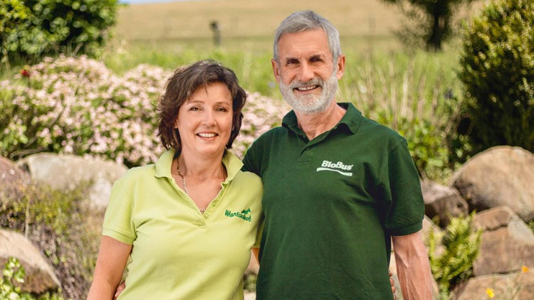 Zwei Personen in grünen Poloshirts mit den Logos \