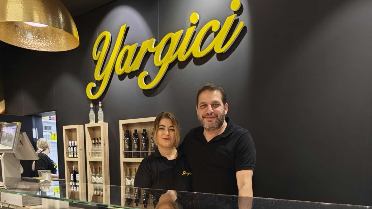 Ein Verkaufsstand mit gelbem Yargici-Schriftzug, Regalen mit Flaschen und einer goldenen Lampe an der Decke.